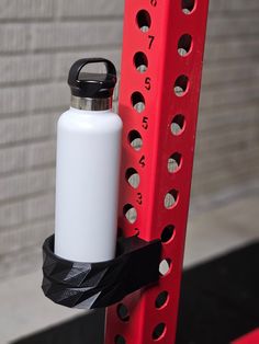 a white water bottle sitting on top of a red rack next to a brick wall