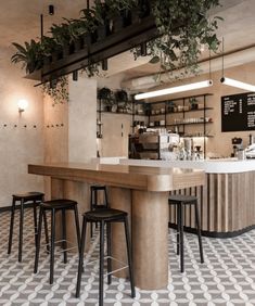 the interior of a restaurant with plants hanging from the ceiling and bar stools at the counter