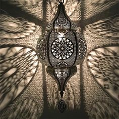 an intricately designed chandelier hangs in the middle of a room with shadows on it