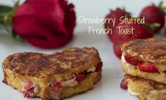 two strawberry stuffed french toast sandwiches on a white plate with strawberries in the background