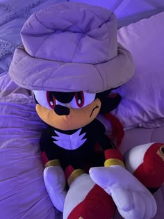 sonic the hedge plush toy sitting on top of a bed with purple sheets and pillows