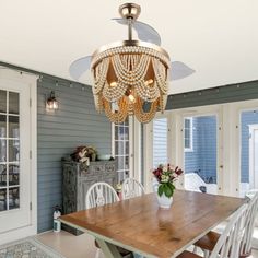 a chandelier hangs from the ceiling above a wooden table in a dining room