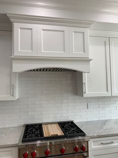 a stove top oven sitting inside of a kitchen next to white cabinets and counter tops