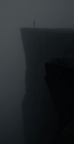 a person standing on top of a cliff in the fog