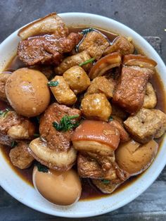 a white bowl filled with meat and potatoes