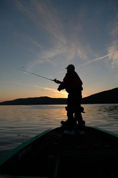 a man standing on top of a boat holding a fishing pole