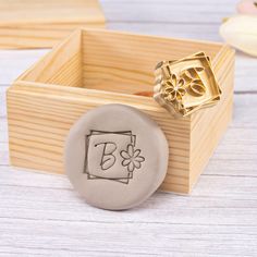 a wooden box with a wax stamp on it and a flower in the middle next to it