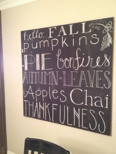 a chalkboard sign hanging on the wall above a dining room table with chairs in front of it