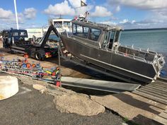 a boat sitting on top of a pier next to the ocean with other boats in the background