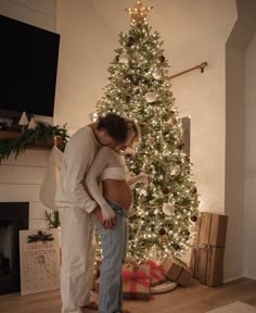 a man and woman standing in front of a christmas tree