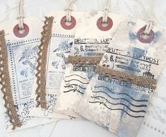 three tags are hanging from twine on a white tablecloth with lace and burlap