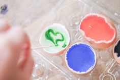 three small cupcakes with different colored icing on them, one is holding a toothpick