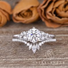 an engagement ring with two pear shaped diamonds on the side, surrounded by roses and petals