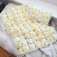 a bed covered in yellow and white lemons on it's sides with pom - poms around the edges