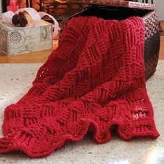 a red knitted blanket sitting on the floor next to a fire place