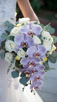 a bride holding a purple and white bouquet