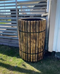 a wooden barrel sitting in the grass next to a fence