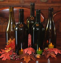 several wine bottles with candles and autumn leaves