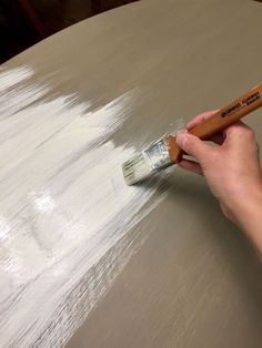 a person is using a brush to paint a table