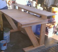 a wooden workbench sitting on top of a floor next to some paint cans