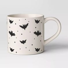 a white coffee mug with bats on the side and stars all over it's surface