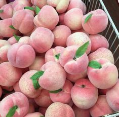 a basket filled with lots of peaches covered in green leaves