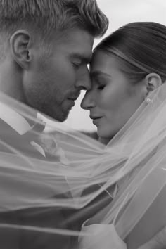 a bride and groom pose for a wedding photo with the veil blowing in the wind