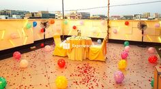 an outdoor party setup with balloons and confetti on the floor, in front of a cityscape