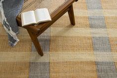 an open book sitting on top of a wooden bench next to a blanket and pillow