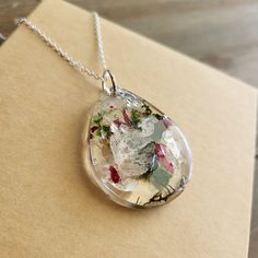 Beautiful White Baby's Breath, Red Rose Flower, And Green Moss Necklace With Real Colorful Flowers In Resin. Delicate Babys Breath Buds Paired With Garnet Red Flowers. Colorful Hues Mingle Together To Create This Naturally Stunning Terrarium Jewelry Piece. Each Pendant Is Uniquely Off-Rounded With Warbling Edges For An Artistic, And Magnifying Affect. This Necklace Pendant Is Two Sided, One Is Smooth And Magnifying, And The Other Is Textured With Real Flowers, Naturally Preserved For Eternal Bea Silver Jewelry With Pressed Flowers In Flower Pendant, Lily Pad Flower, Silver Flower Necklace With Pressed Flowers Pendant, Resin Necklace Pendant Flower, Turquoise Cross Necklace, Resin Necklace With Pressed Flowers In Round Pendant, Moss Necklace, Gray Beaded Necklace, Ivory Necklace