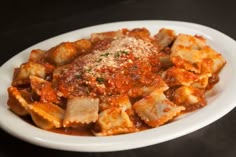 pasta with sauce and parmesan cheese in a white bowl on a black table