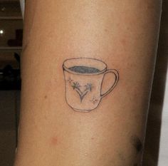 a tattoo on the arm of a woman with a cup of coffee