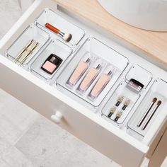 an open drawer with various cosmetics and makeup products in it on a countertop next to a sink