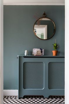 a blue cabinet with a mirror above it in a room that has black and white checkered flooring