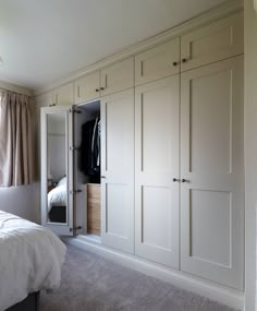 a bedroom with white closets and carpeted flooring