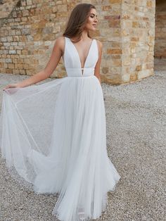 a woman in a white dress is standing outside with her back to the camera and she's wearing a long flowing veil