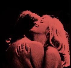 a man and woman kissing in the dark with red light coming from their faces behind them