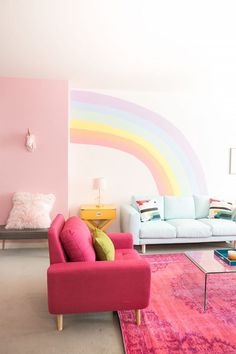 a living room filled with furniture and a rainbow painted wall