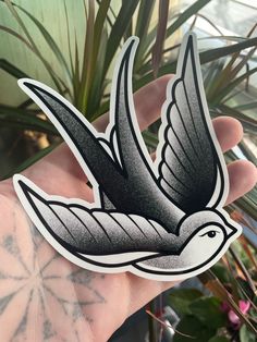 a hand holding a sticker with a bird in the air on it's side