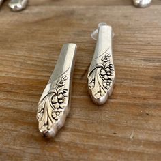 two silver spoons sitting on top of a wooden table