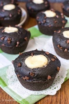 chocolate cupcakes with white frosting on a green and white napkin next to some cookies