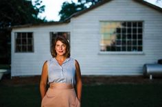 a woman standing in front of a white house at night with her hands on her hips