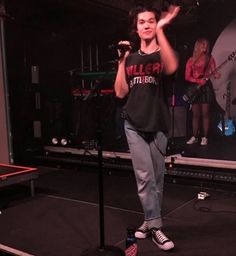 a woman standing on top of a stage holding a microphone in front of her face