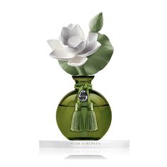 a green vase with a white flower in it