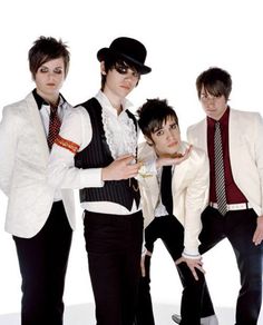 four young men dressed in black and white posing for the camera