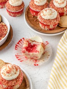 cupcakes with white frosting and red sprinkles on wooden plates