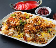 a white plate topped with rice and meat next to bowls of sauces on a table