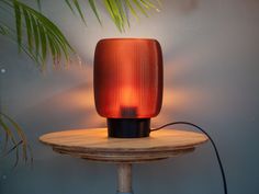 an orange lamp sitting on top of a wooden table next to a potted plant