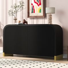 a black and gold sideboard in a living room next to a painting on the wall