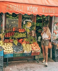 a woman standing in front of a fruit stand